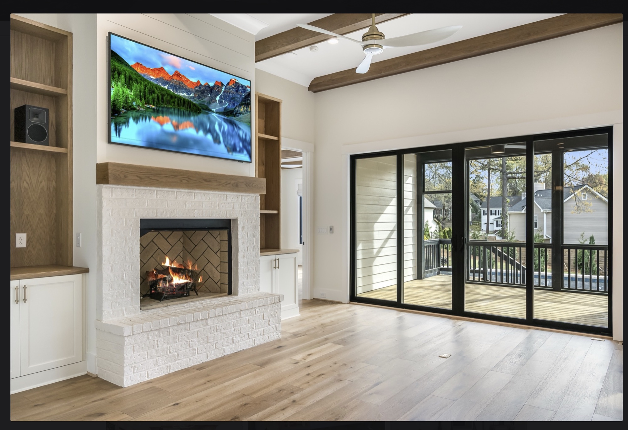 Family room with white-brick fireplace, exposed beams, and view to the screened porch