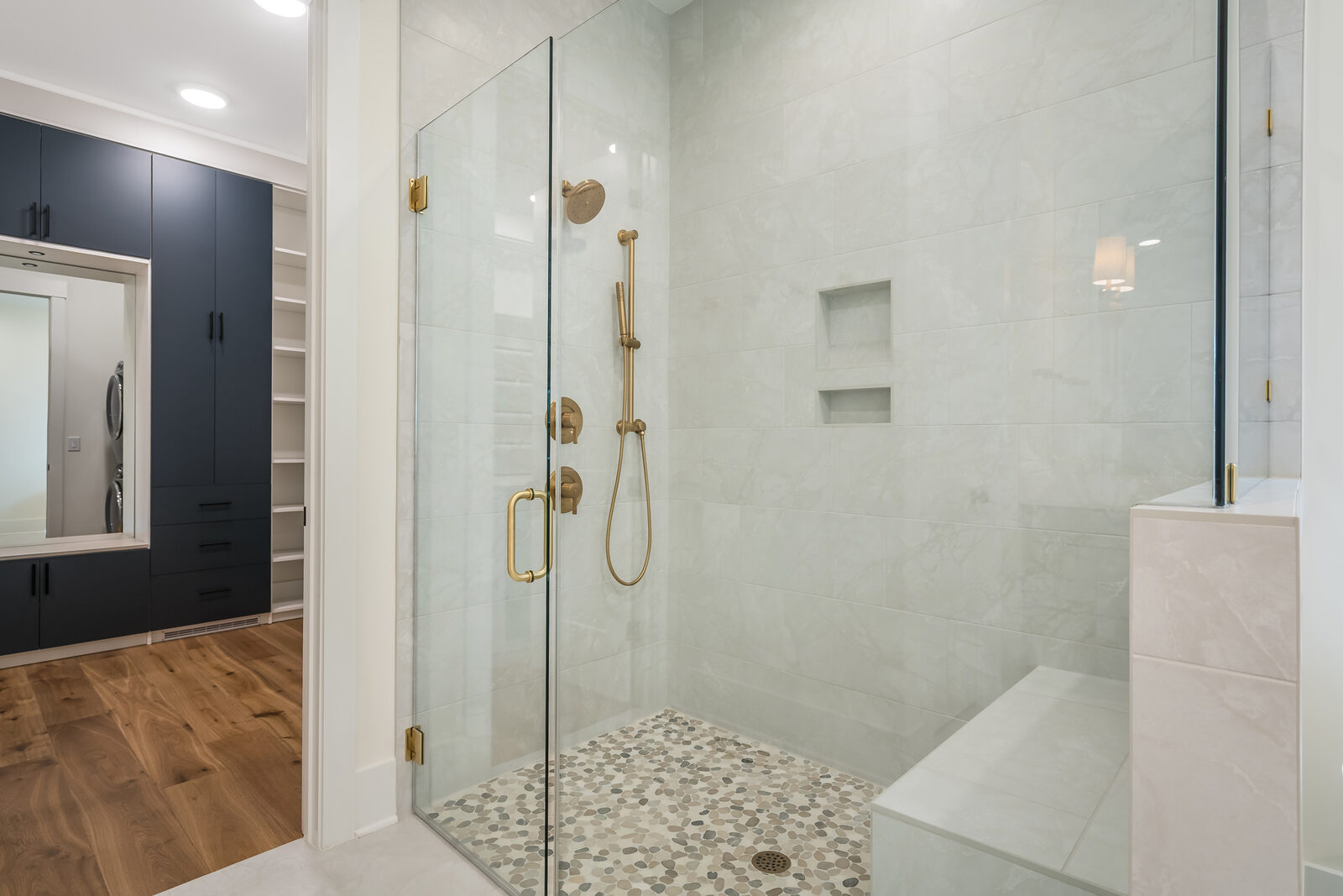 Frameless glass spa shower with brass fixtures in a Gemstone bath